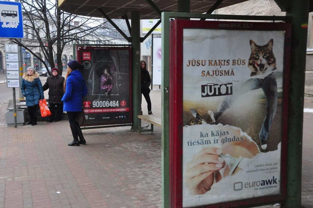 Said ad on a bus stop shelter, but vertical and in Latvian: Jūsu kaķis būs sajūsmā, jūtot, ka kājas tiešām ir gludas (your cat will be delighted when it feels the legs are really smooth!)

Behind it is a public service ad about domestic violence (i think?). Your cat will not be delighted about that.
